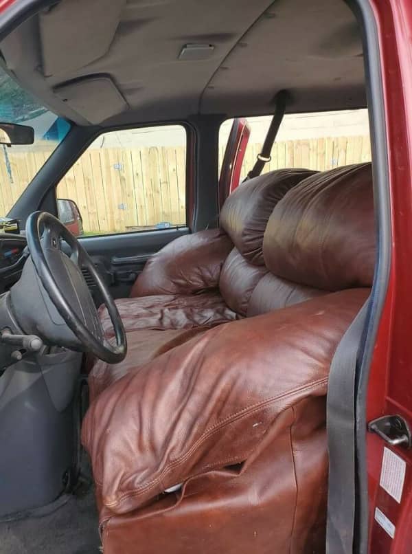 Oversized brown leather recliner sofa crammed into truck cab as driver seat replacement