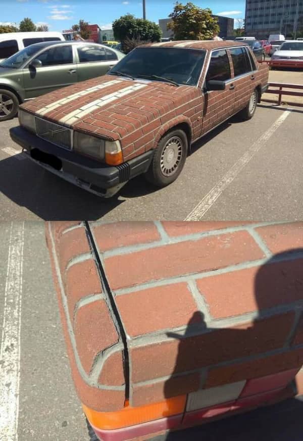 Old Volvo sedan covered entirely in realistic brick pattern wrap or textured material