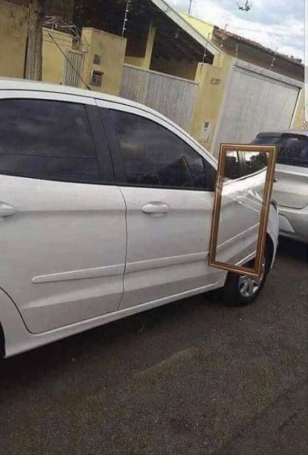 White sedan with full-length framed wall mirror duct-taped to door replacing side mirror
