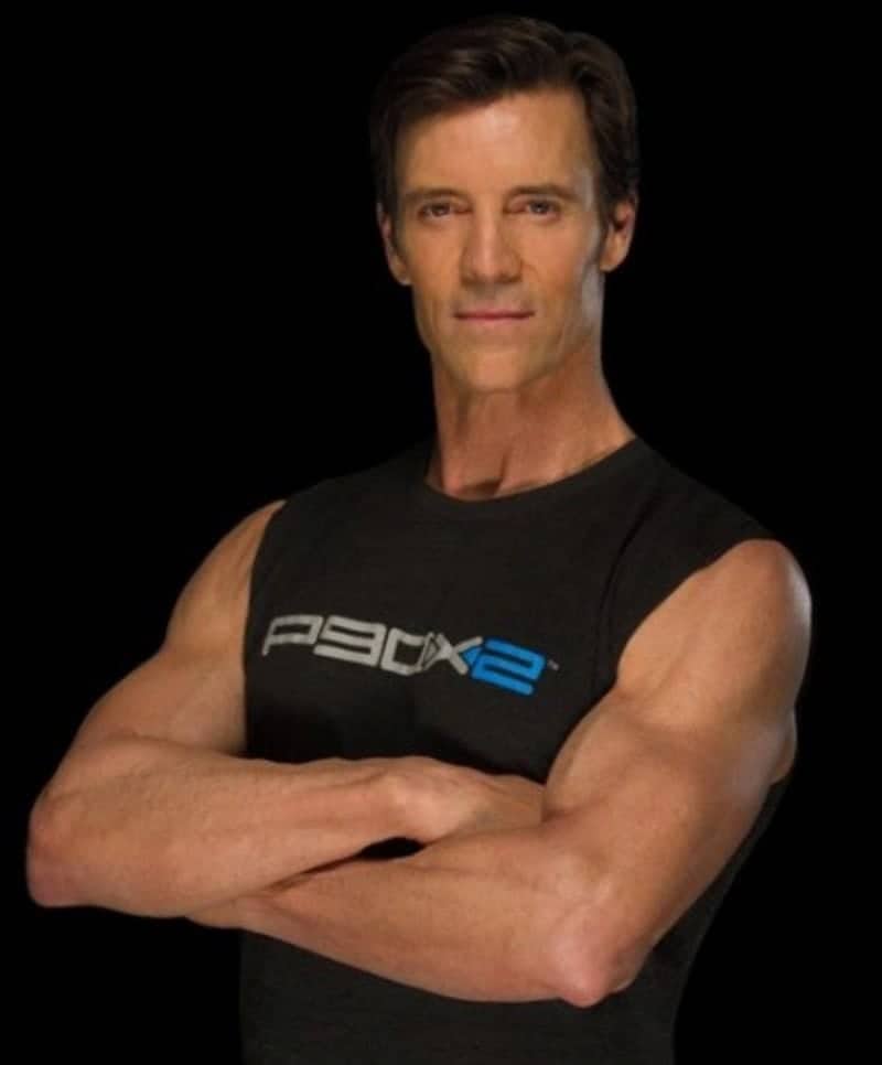 P90X2 fitness program trainer posed with arms crossed wearing black sleeveless shirt