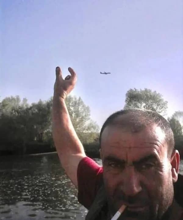 Perspective photo of a man appearing to pinch a small distant airplane with his fingers outdoors.
