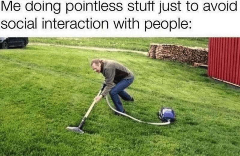 A hilarious introvert meme depicting a man in a yard literally using a vacuum cleaner on his grass. The text above explains the extreme measure: "Me doing pointless stuff just to avoid social interaction with people:".