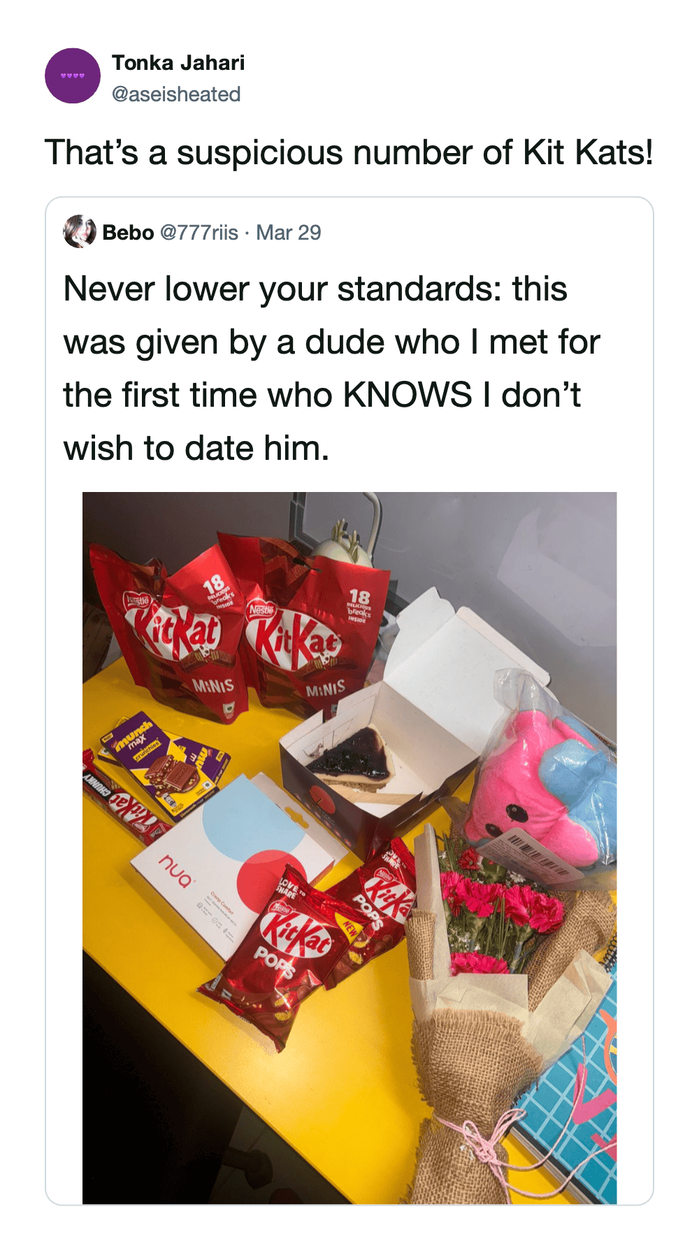 suspicious KitKat heist meme quote-tweet by Tonka Jahari. The original post shows a yellow desk overflowing with "gifts" from a first date, including multiple large bags of KitKat Minis and KitKat Pops. The caption jokingly connects the excessive candy haul to the recent theft.