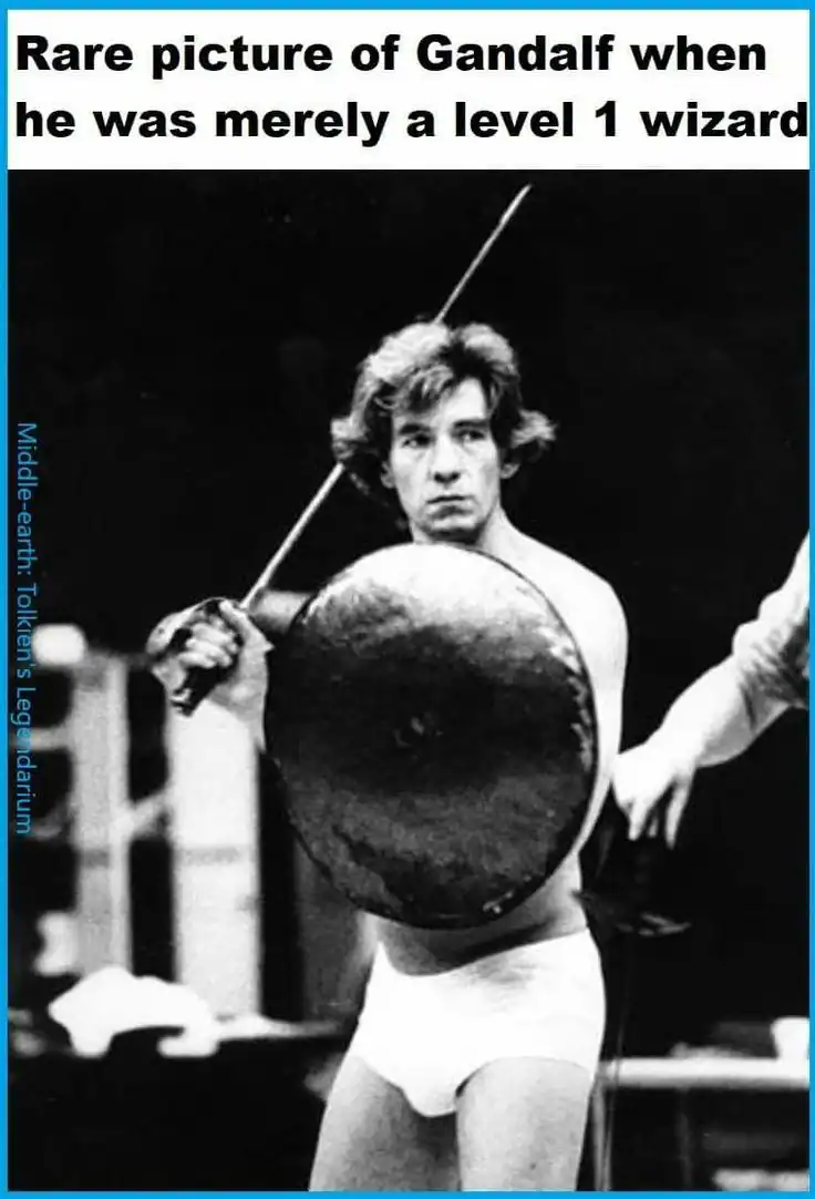 vintage black-and-white lotr meme photo of a young Ian McKellen standing on a stage wearing only white underwear, holding a sword and a round shield. The caption reads: "Rare picture of Gandalf when he was merely a level 1 wizard."