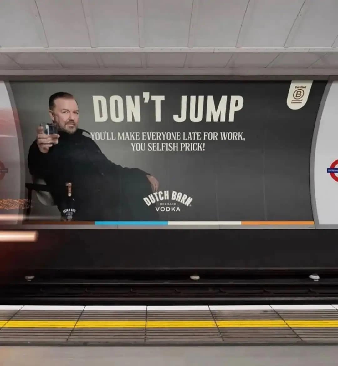 dark humor meme dump billboard advertisement for Dutch Barn Orchard Vodka featuring Ricky Gervais holding a glass. The large text reads, "DON’T JUMP. YOU’LL MAKE EVERYONE LATE FOR WORK, YOU SELFISH PRICK!"