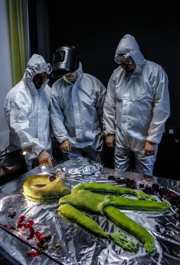 hilarious meme from a meme dump showing three researchers in full white hazmat suits performing a mock "autopsy" on a green alien body made entirely of guacamole or green dough, with one person inexplicably wearing a welding mask.