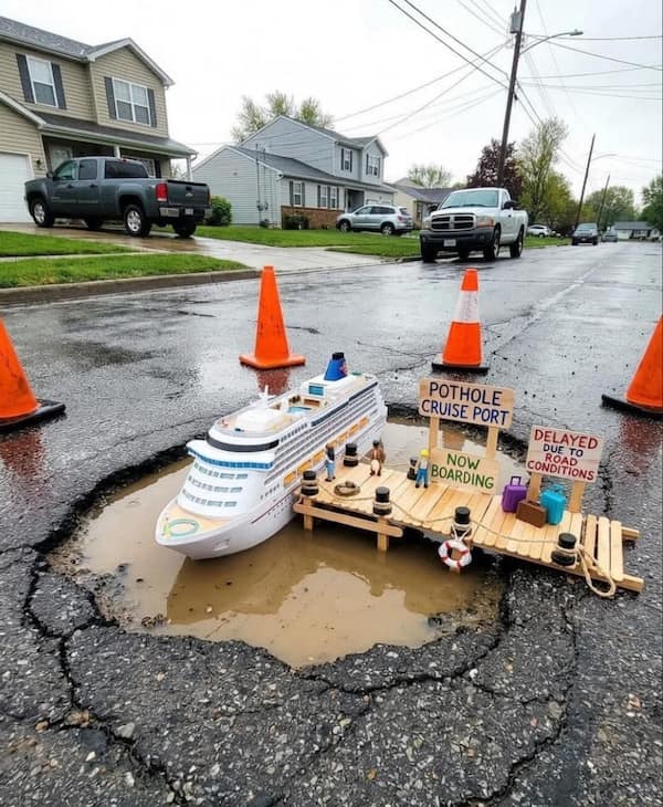 creative hilarious meme where a massive, water-filled pothole is staged as a miniature "Pothole Cruise Port," complete with a toy cruise ship, a popsicle-stick dock, and tiny "Now Boarding" signs.