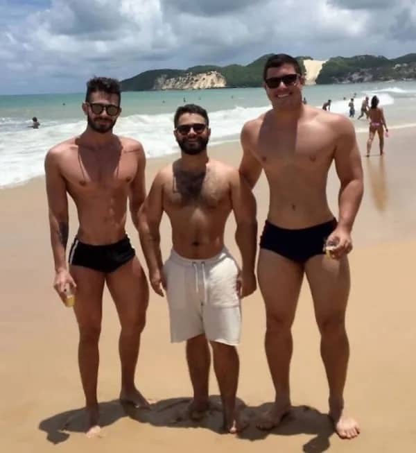 Three men posing at beach with one man's legs digitally stretched unnaturally long
