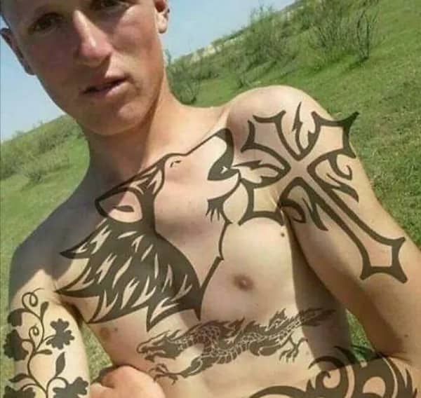 Shirtless young man showing off flat digitally added wolf cross and dragon tattoos