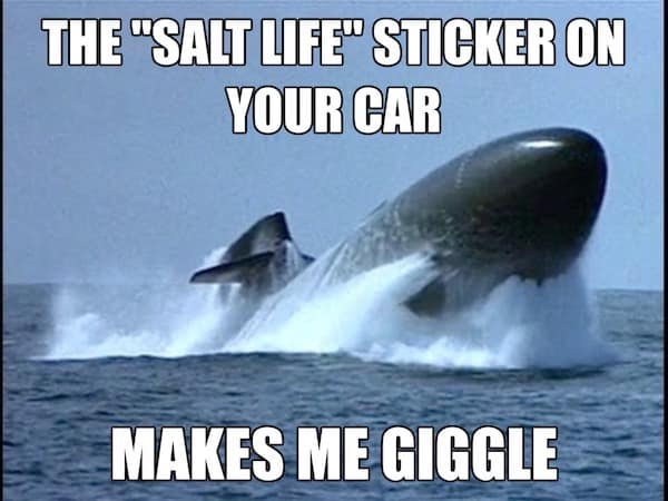 A snarky submarine meme showing a massive nuclear submarine breaching the water surface at a high angle. The text mocks civilian beach culture: "THE 'SALT LIFE' STICKER ON YOUR CAR MAKES ME GIGGLE."