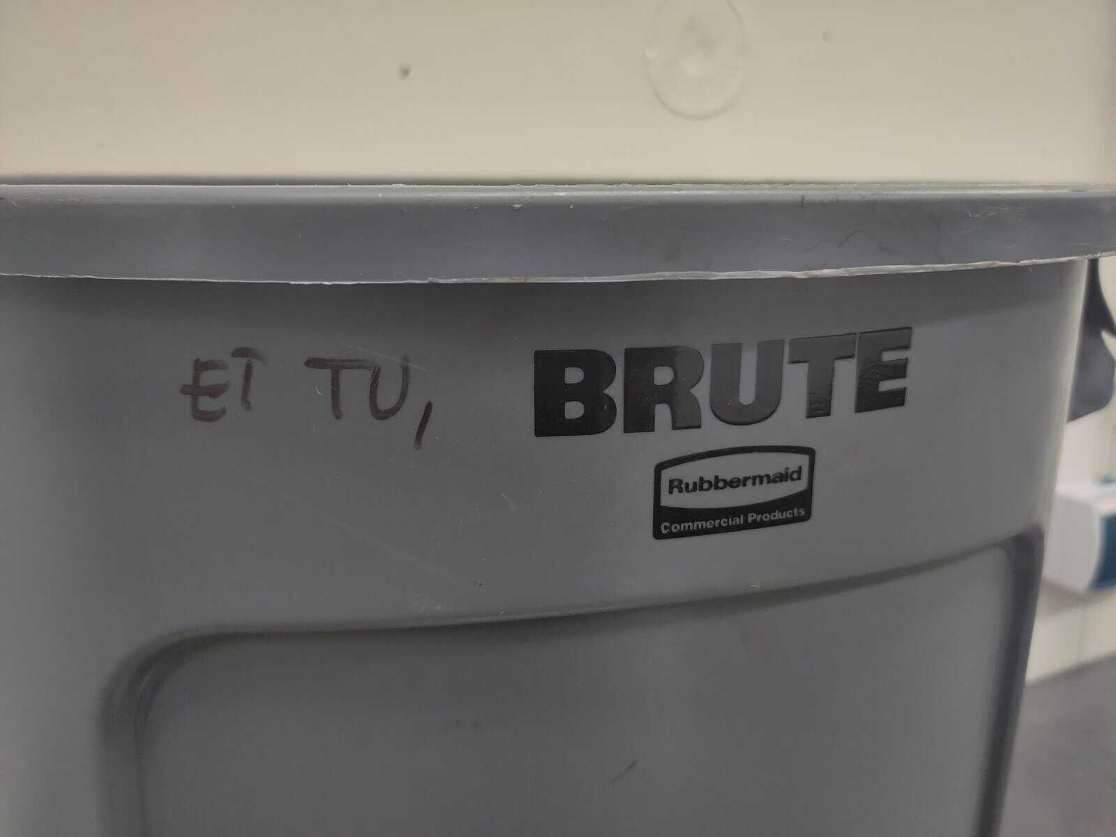 An intellectual instance of wholesome vandalism on a grey industrial trash can. Someone has used a black marker to write "ET TU," before the embossed brand name "BRUTE," creating a literary reference to Julius Caesar’s final words.