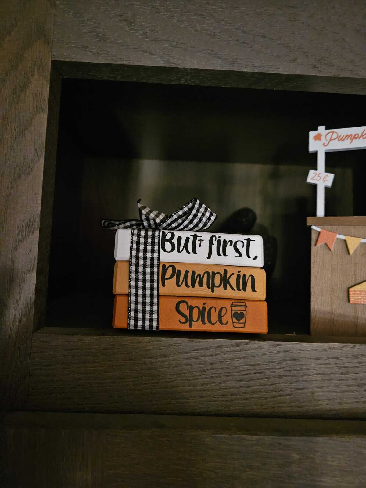 decorative wooden block stack featuring the phrase "But first, Pumpkin Spice." Juvenile wholesome vandalism has added a small "t" after the word "But" with a marker, transforming the basic autumnal sentiment into "Butt first, Pumpkin Spice."