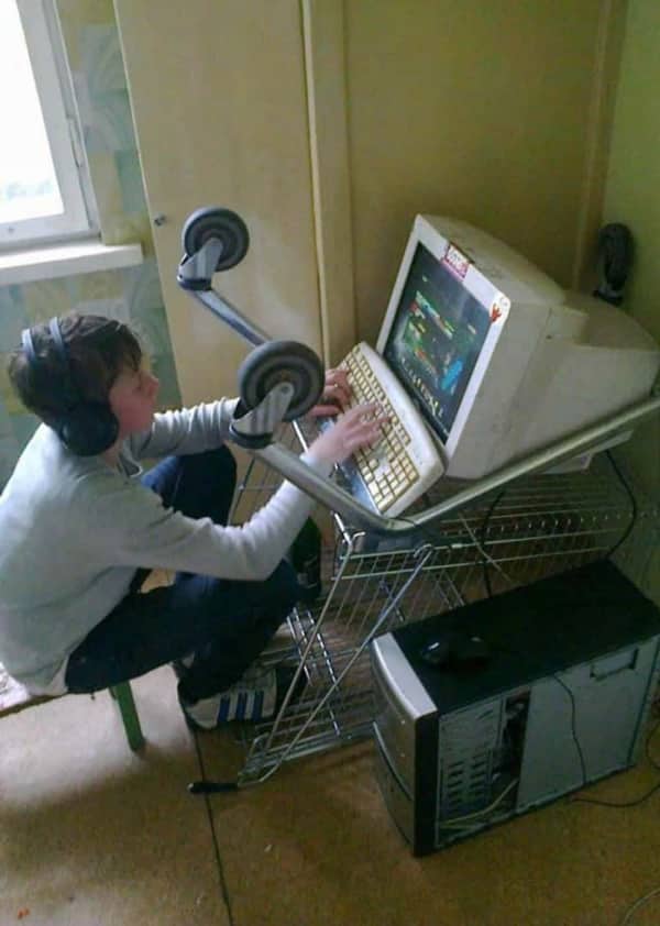 Kid gaming on old CRT monitor balanced on upside-down shopping cart as a desk