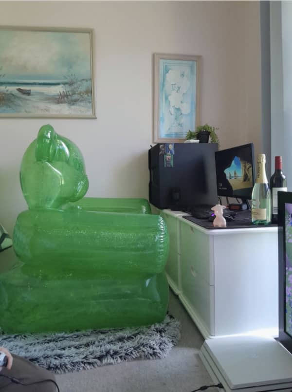 Inflatable green alien chair gaming setup facing dual monitors on a white dresser