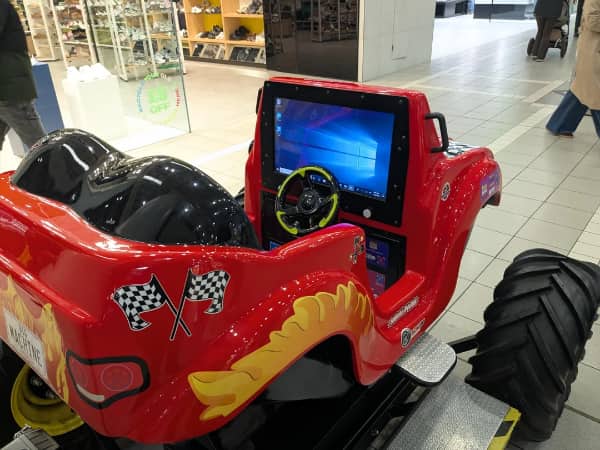Windows 10 tablet mounted inside red kids ride-on toy car in shopping mall