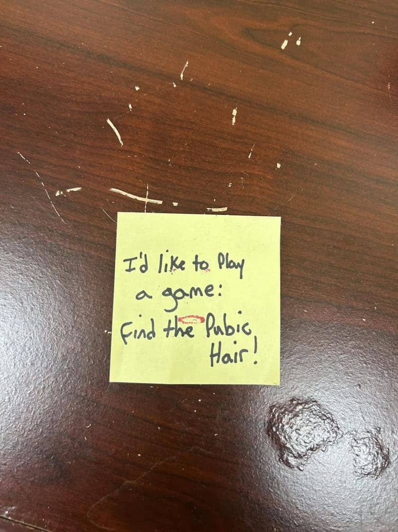 Passive aggressive sticky note on dirty office surface daring coworkers to find something disgusting