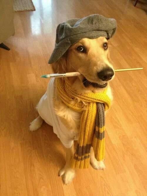 A golden retriever dressed as a classical French artist, complete with a grey beret, yellow knit scarf, and holding a paintbrush gently in its mouth.
