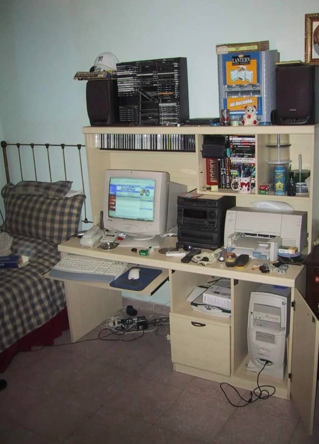 Bedroom computer hutch loaded with a CRT monitor, stereo, printer, and stacks of CDs.