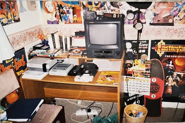 Gaming desk with a small TV, several retro consoles, and anime and Castlevania posters.