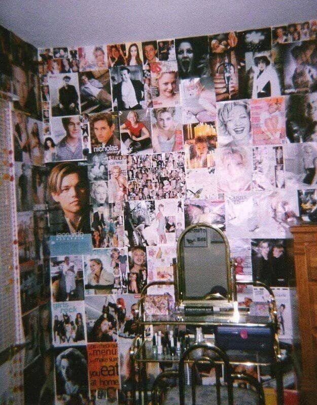 Bedroom wall completely covered in magazine clippings of 90s celebrities above a brass vanity.