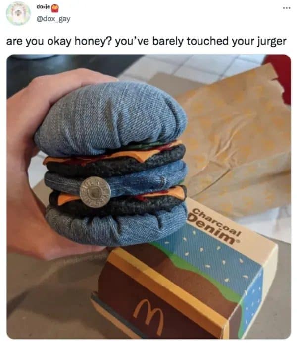 Hand holding a burger made of stitched denim over a McDonald's box, captioned jurger.