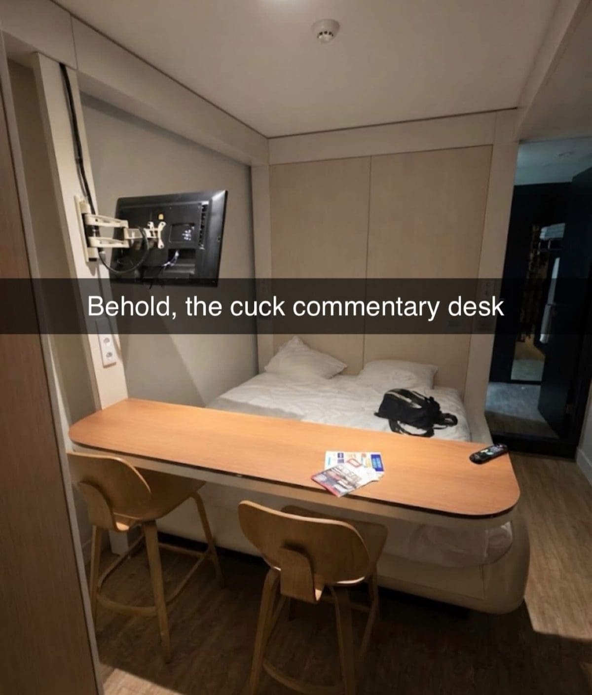 Tiny hotel room with a bar counter and stools facing the bed, captioned with a crude joke.