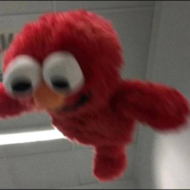 Blurry Elmo plush flying straight toward the camera with arms outstretched in midair