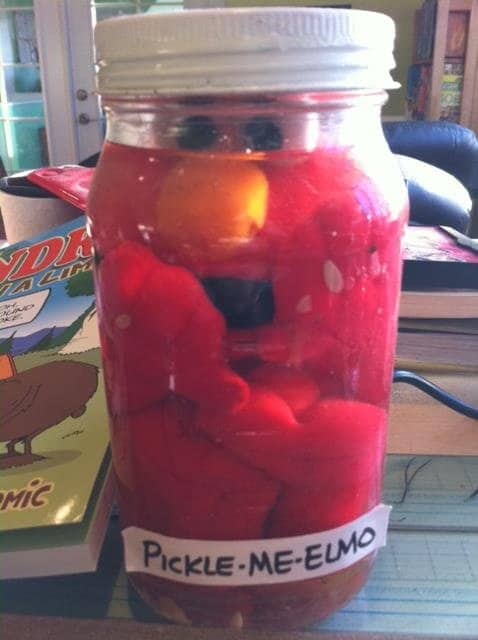 Elmo plush submerged in red liquid inside a mason jar labeled Pickle Me Elmo