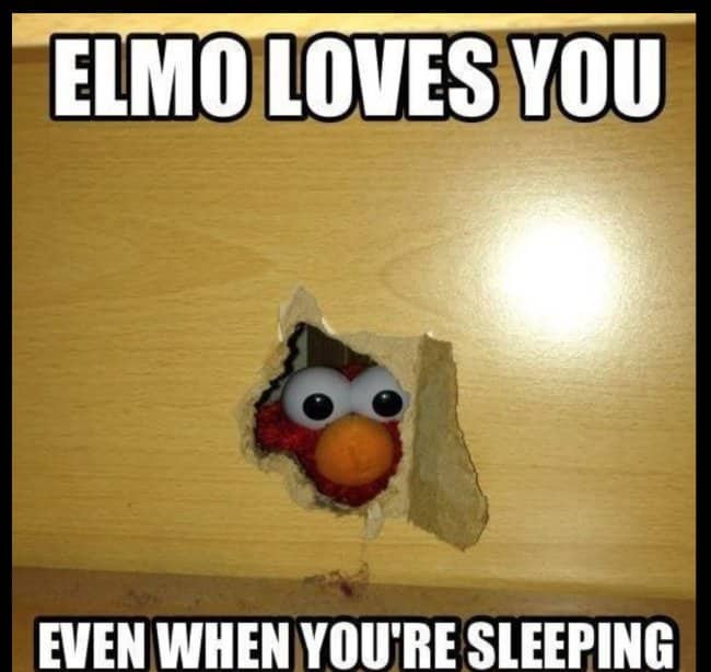 Elmo face peeking through a hole torn in a wooden wall, captioned Elmo loves you while sleeping
