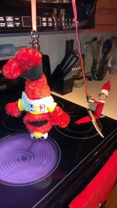 Elmo plush hung upside down over a stovetop by an Elf on the Shelf holding a knife