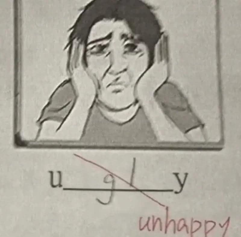 Sad face drawing with ugly crossed out by the teacher and replaced by unhappy.