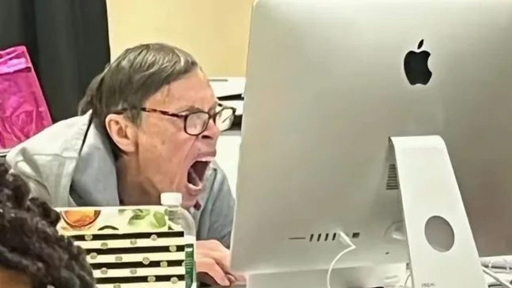 Older man yelling at a computer monitor with his mouth wide open, the exact mood of scrolling late night memes on The Nightcap.