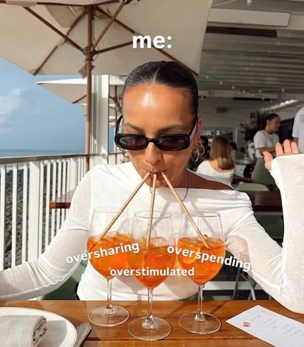 Woman sipping three spritz glasses labeled oversharing, overspending and overstimulated in a meme dump.