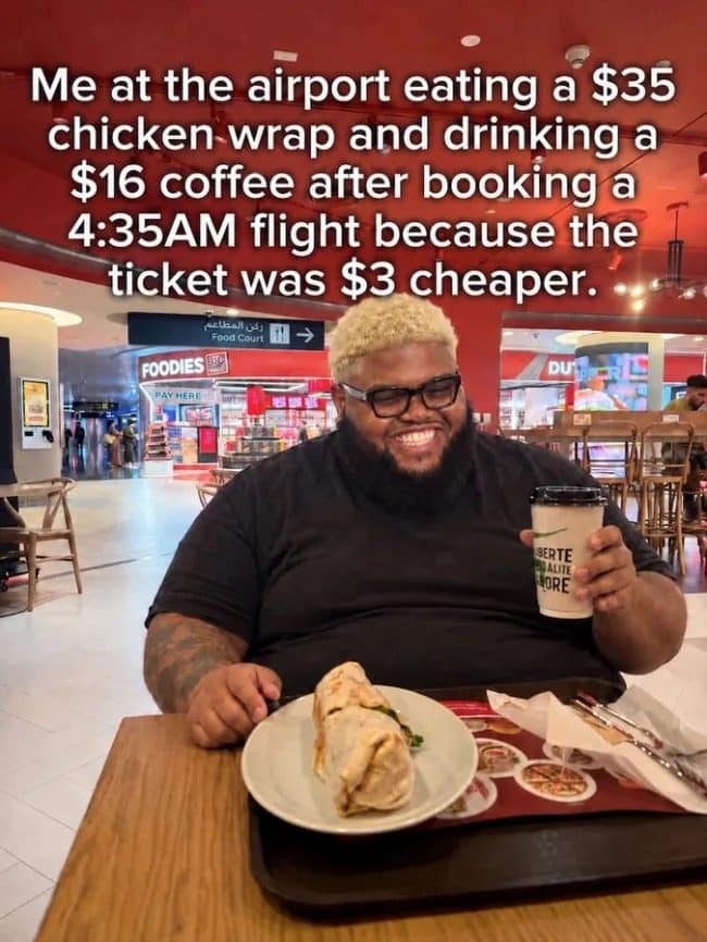 Smiling man at an airport food court with a $35 chicken wrap and $16 coffee.