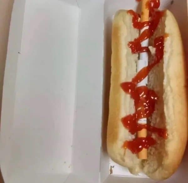 A hot dog bun with ketchup and a paper-wrapped straw where the sausage should be.