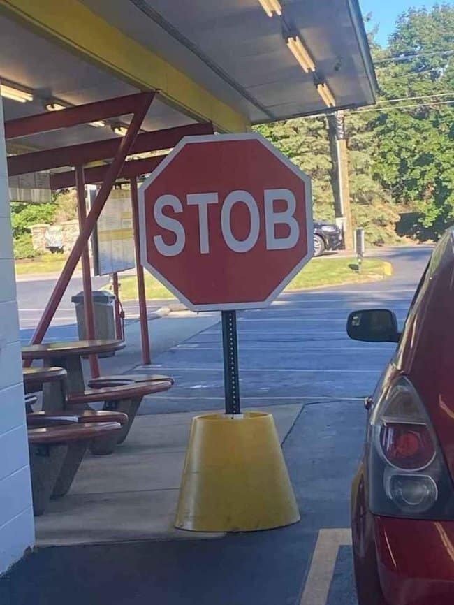 Red stop sign on a yellow base at a drive-in that reads STOB.