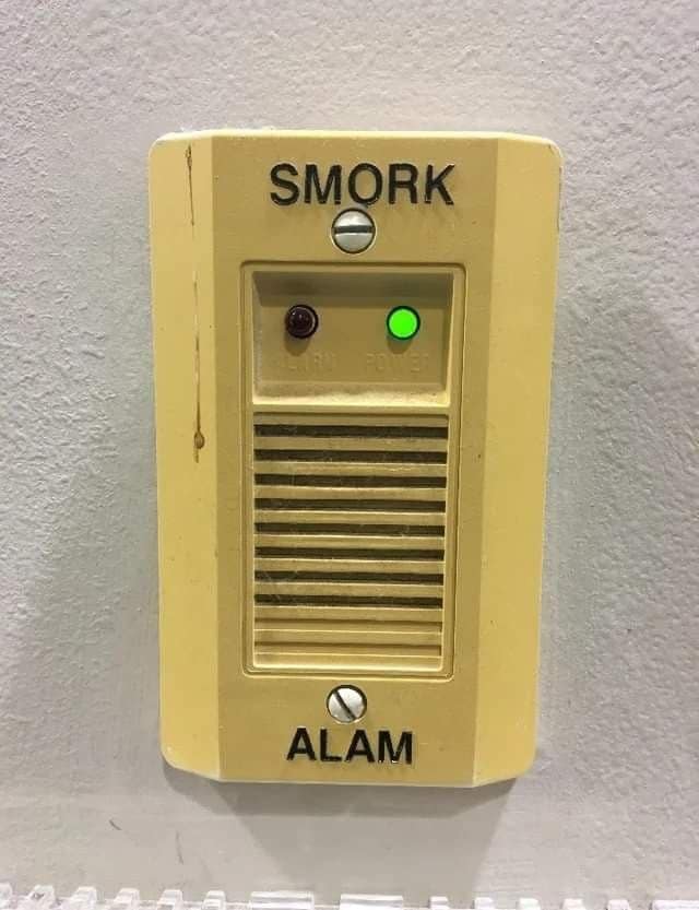 Yellow wall alarm unit labeled SMORK ALAM instead of smoke alarm.
